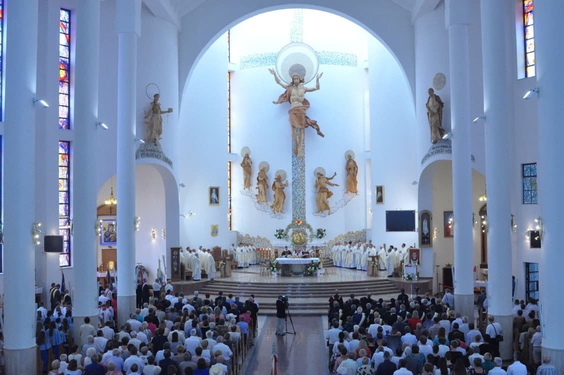 Wnętrze kościoła z rzeźbioną kompozycją ołtarzową w tle podczas uroczystej mszy